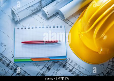 Safety building helmet checked notebook pen blueprints on construction plan. Stock Photo