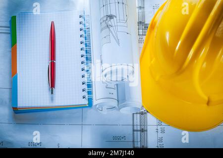 Safety building helmet checked notebook pen blueprints on construction plan. Stock Photo