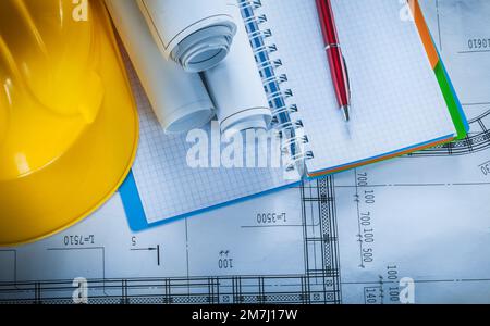 Safety hard hat checked notebook pen blueprints on construction plan. Stock Photo