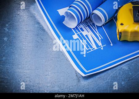 Set of blue blueprints measuring tape on scratched metallic background. Stock Photo