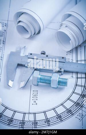 Stainless screw bolt with nut slide caliper rolls of construction plans on blueprint architecture and building concept. Stock Photo