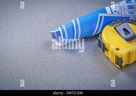 Tape-line blue rolled blueprint on grey background construction concept. Stock Photo