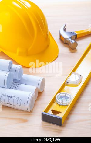 white blueprints construction level yellow helmet claw hammer on wooden board Stock Photo