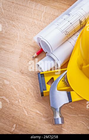 yellow helmet claw hammer level rolled blueprints pencil on wooden boards construction concept Stock Photo