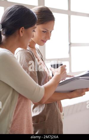 These figures look promising. two female colleagues looking over a document. Stock Photo