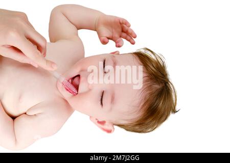 Mother hands are brushing the teeth of a happy toddler baby boy, isolated on a white background. Mom brushes child mouth with a toothbrush, isolated o Stock Photo