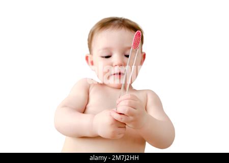 Child cleans his mouth with a toothbrush in his hands, isolated on a white background. Happy toddler baby learns to brush her teeth while lying on her Stock Photo