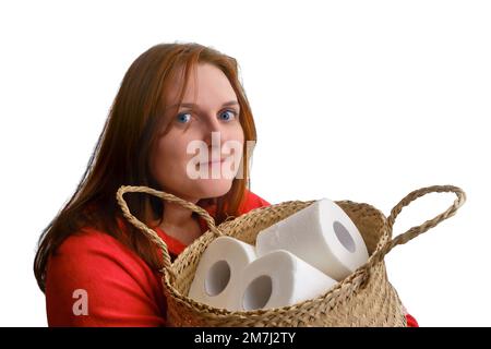 A woman holds rolls of toilet paper in a large basket, close-up, isolated on a white background. Problems with toilet paper in the shops because of th Stock Photo