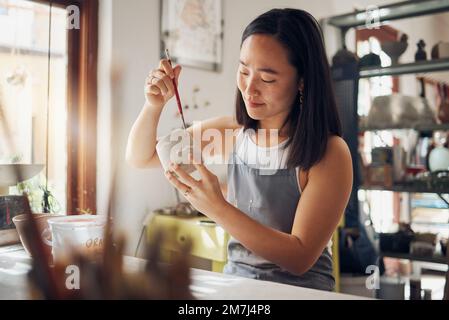Pottery, art and design with an asian woman in a studio for her creative ceramics hobby as an artisan. Manufacturing, pattern and artist with a female Stock Photo
