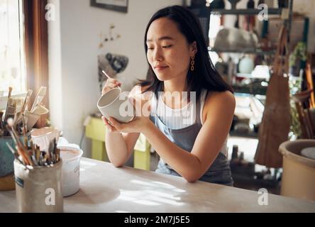 Pottery, art and sculpture with a japanese woman in a studio for design or a creative hobby as an artisan. Manufacturing, pattern or artist with a Stock Photo