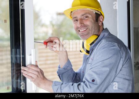 happy man drilling a window frame Stock Photo