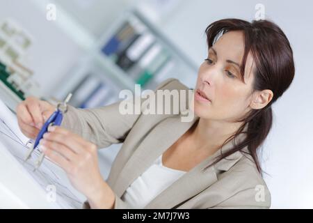 female drawing blueprints using rulers compasses and pencils Stock Photo