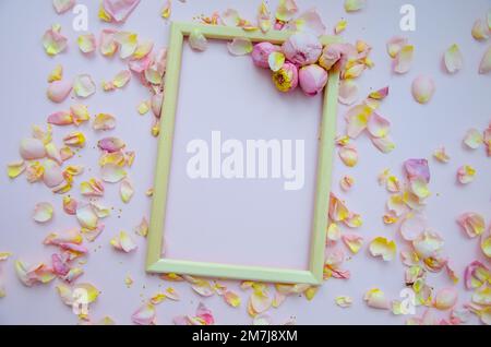 Rose petals, rose buds and empty wooden frame on light pink background. Flat lay, copy space. Mother's Day, St. Valentine's Day, March 8 concept. Top Stock Photo