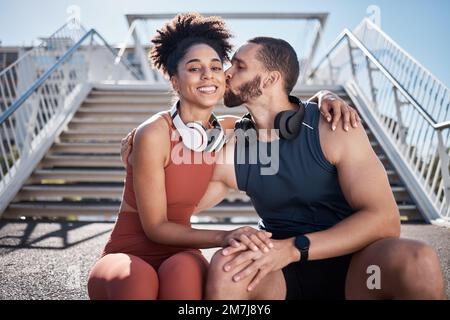 Sports, love and man kissing woman on stairs in city on break from exercise workout. Motivation, health and fitness goals, couple rest and kiss with Stock Photo
