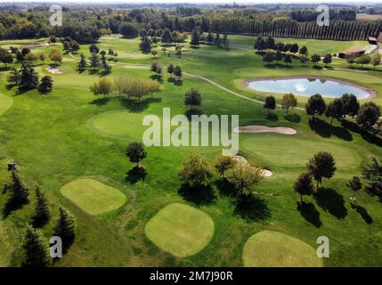 Aerial landscape of course of golf with green grassy meadows and ponds among trees in sunlight Stock Photo