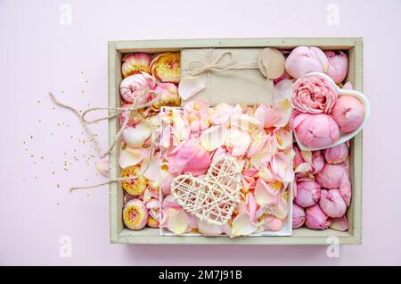 Gift box and rose buds and petals. Fresh flowers, craft gift, straw tangled heart. Roses in a box pink roses, yellow roses. Fashion. Minimalism. Valen Stock Photo