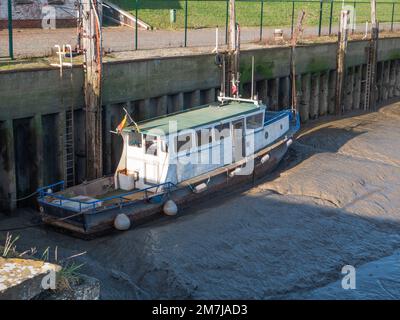 Old weathered boat lies in the mud at low tide Stock Photo