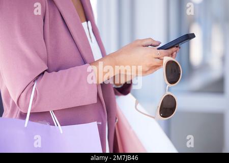 Woman, phone and shopping with sunglasses in hands while doing online shopping, ecommerce and internet banking. Female using mobile app for customer Stock Photo