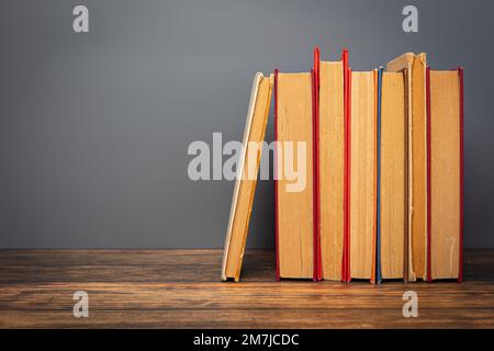 Composition with vintage old hardback books, on wooden table and gray background. stack of books. Back to school. Education. Stock Photo