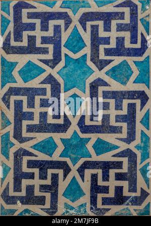 Ancient blue, white and turquoise decorative ceramic tile with swastika and star pattern on medieval tomb, Uch Sharif, Bahawalpur, Punjab, Pakistan Stock Photo