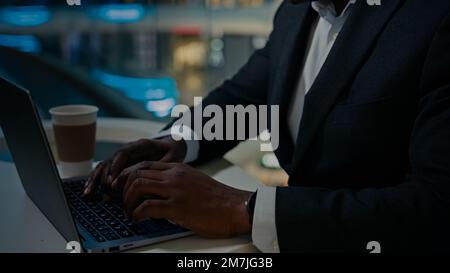 Close up unrecognizable African American businessman ethnic old senior mature man worker male typing laptop at table in cafe. Cropped view Stock Photo