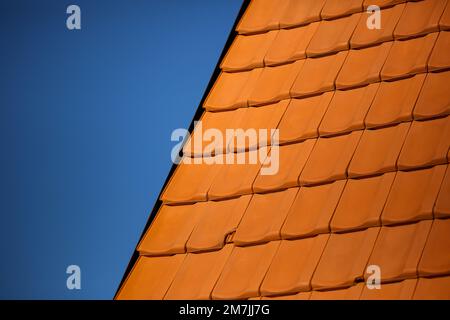 Details of orange brick tile roof patterns with clear bright blue sky in the background. Close-up of House Architecture patterns. Stock Photo