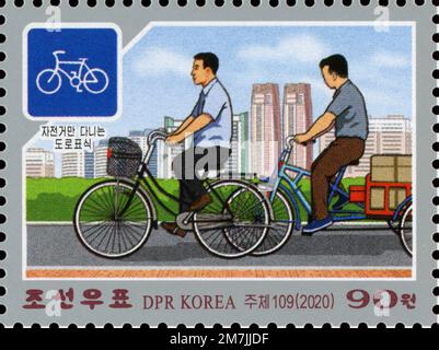 2020 North Korean postage stamp depicting men riding bicycles on a dedicated lane with a traffic sign, illustrating traffic rules. Stock Photo