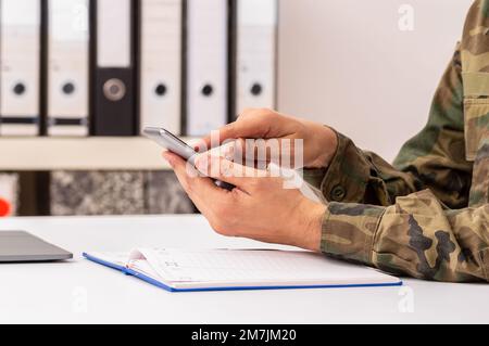 Closeup shot of an unrecognizable military man hands with agenda using phone at office Stock Photo