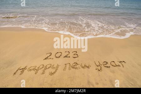 2023 happy new year handwritten in sand on a beautiful beach Stock Photo