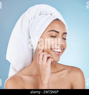 Woman, facial care and happy with towel for luxury beauty vision, salon spa cleaning and closed eyes in blue background studio. Young model, smile and Stock Photo