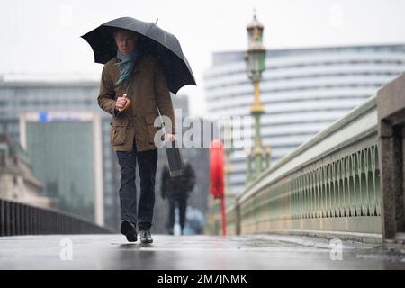 People walk along Westminster Bridge, central London in the rain. The Met Office has issued warnings for heavy rains and floods, falling heaviest in western areas but causing wet and windy conditions all over the country. Picture date: Tuesday January 10, 2023. Stock Photo