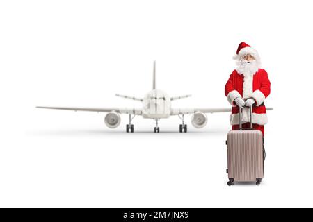 Full length portrait of santa claus standing with a suitcase in front of an airplane isolated on white background Stock Photo