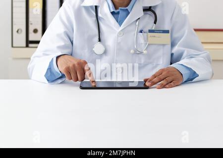Cropped shot of a male doctor using a digital tablet in hospital office. Stock Photo
