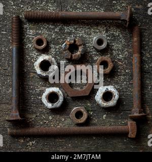 Arrangement of rusty nuts and bolts on a textured wooden surface Stock Photo