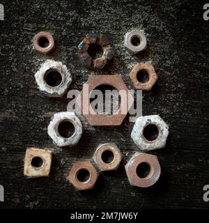 Collection of various nuts and bolts arranged on a rustic wooden surface Stock Photo