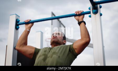 Man is doing pull ups exercises on horizontal bar Stock Photo