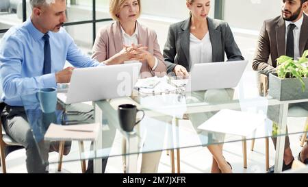 group of business people discussing something while sitting at a Stock Photo