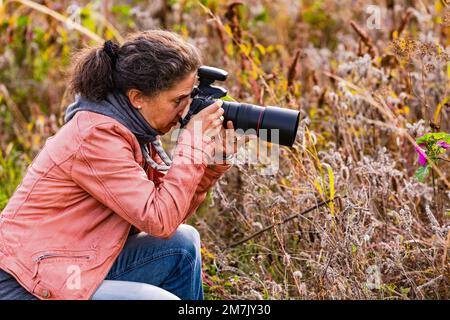 Pretty woman isolated as photographer with professional dslr camera in rural nature in autumn Stock Photo