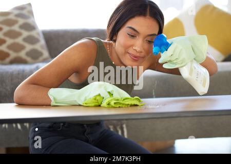 Woman, cleaning service and spraying living room table for bacteria, dust and dirt for health, wellness and safety in house or apartment. Happy Stock Photo