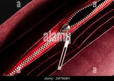 An open zipper on a red leather item or wallet. Stock Photo
