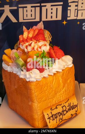 Japan, Honshu, Tokyo, Coffee Shop Window Display of Loaf Topped with Cream and Fruits with Happy Birthday Sign Stock Photo