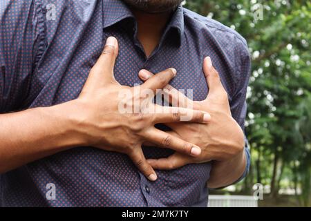 young man suffering pain in heart and holding chest with hand  Stock Photo