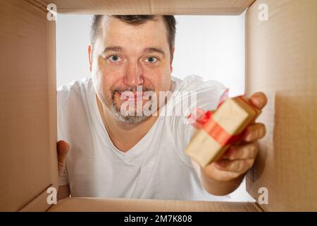 Happy man unpacking, opening carton box and looking inside. Man smiling unpacking and carton box Stock Photo