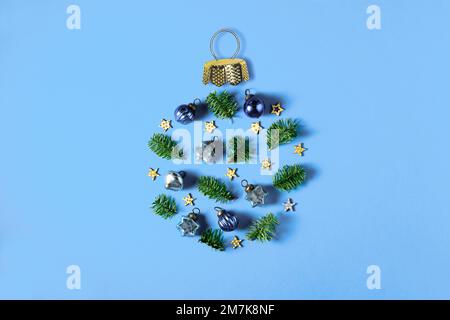 Christmas decorations, stars and fir twigs laid in a circle, shape of Xmas ball, bauble, trinket. Flat lay on blue background. Simple minimal concept. Stock Photo