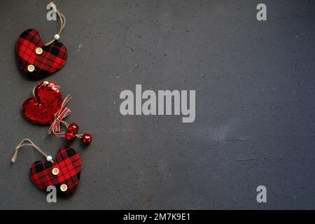 Three heart shapes made of cloth on a grey background Stock Photo