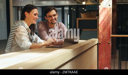 business professionals joining an online conference on a laptop. Two business people connecting with their clients while sitting in a coworking office Stock Photo