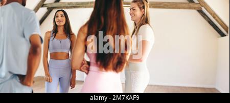 Panoramic view of a group of sporty people talking to each other while standing in a circle. Group of happy friends sharing mental wellness tips durin Stock Photo