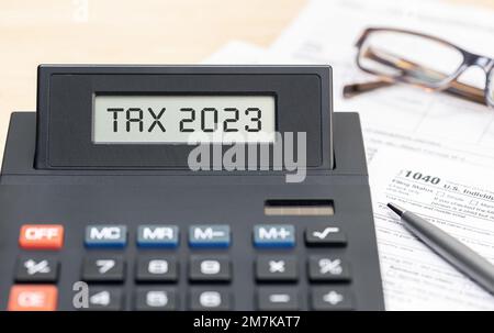 Tax time 2023 concept. Text on calculator screen and tax form on table Stock Photo