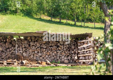 Stack of chopped wood for winter fire making on the picturesque green summer field in Pyrenees, France. Stock Photo