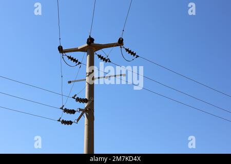 Power line post with electrical wires and capacitors on blue sky background. Electricity transmission line, power supply Stock Photo